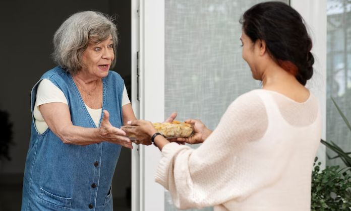A girl is giving food to an old woman.