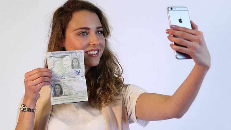 a girl taking a picture with her passport for safty in travel