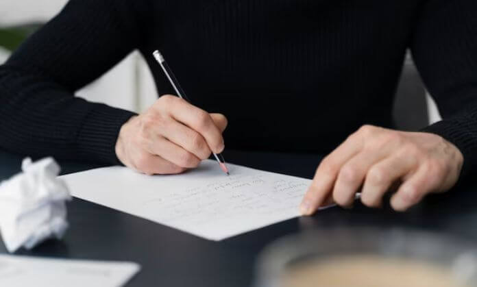a man writing letter on paper.