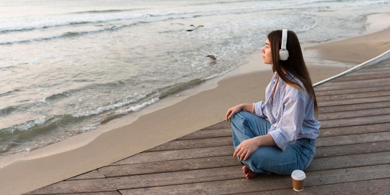 a person sitting on a dock with headphones on 
