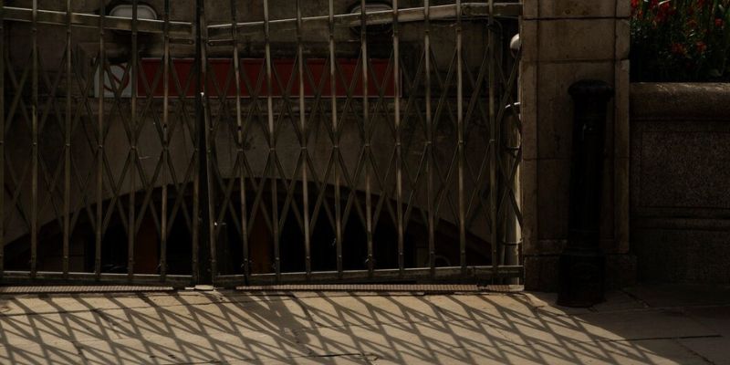a metal gate with a shadow on the ground