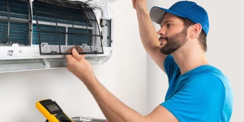 a person in a blue hat fixing a air conditioner