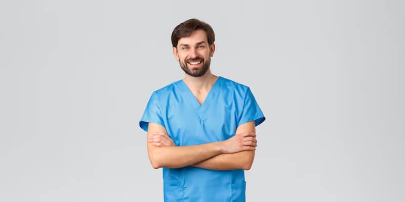 a person in blue scrubs with his arms crossed 