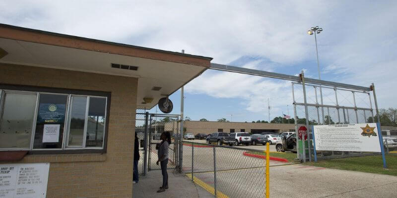 a building with a fence and cars in the background