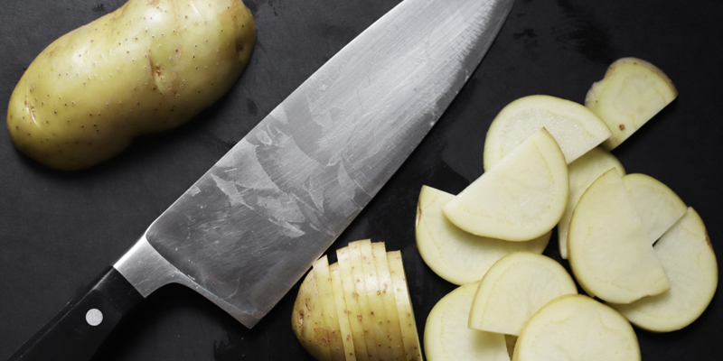 a knife next to sliced potatoes 